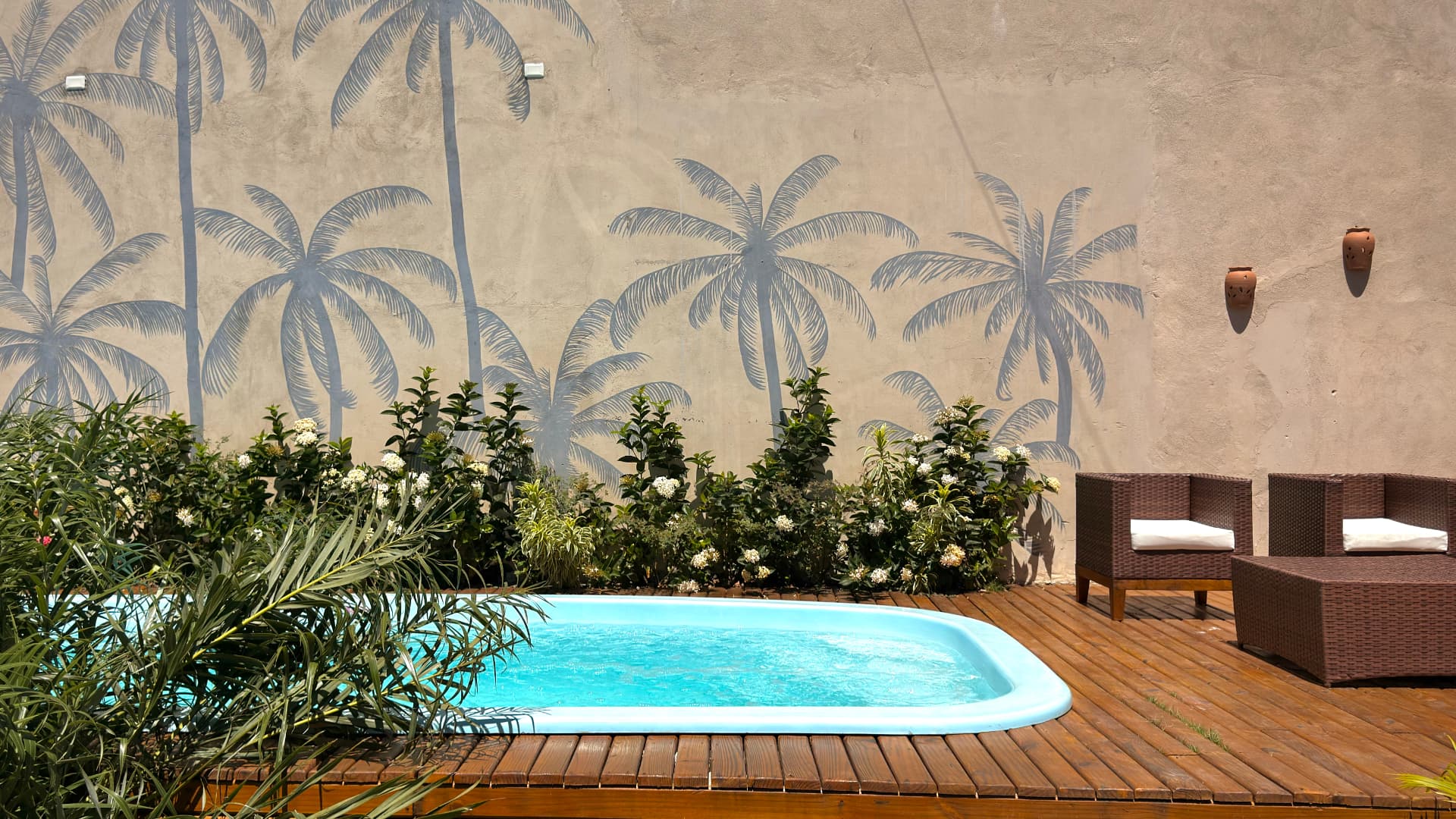 Piscina privativa com mural de coqueiros pintado na parede